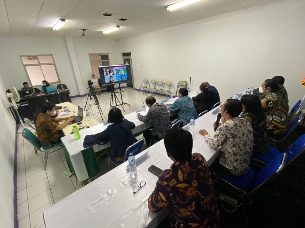 A group of people sitting at a table watching a presentation Description automatically generated with low confidence